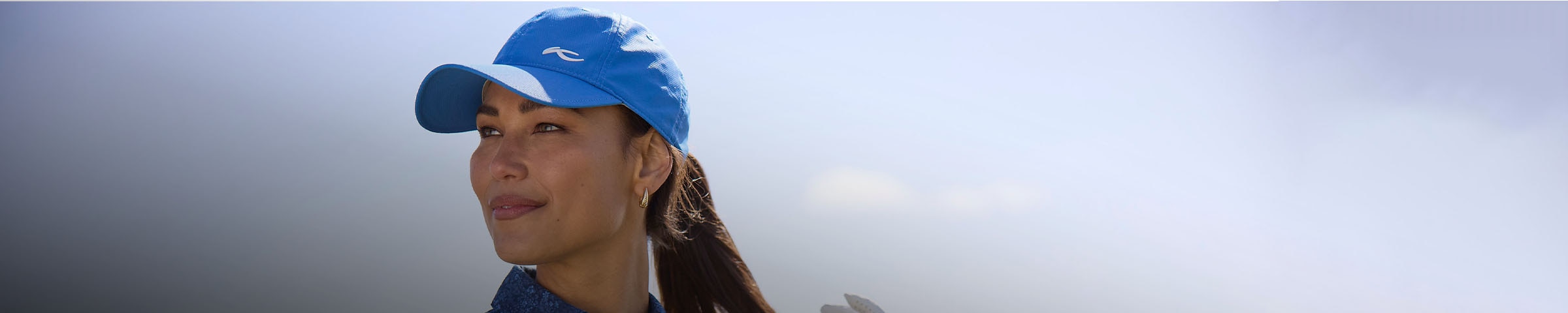 A woman wearing a blue KJUS cap looks out on the course.