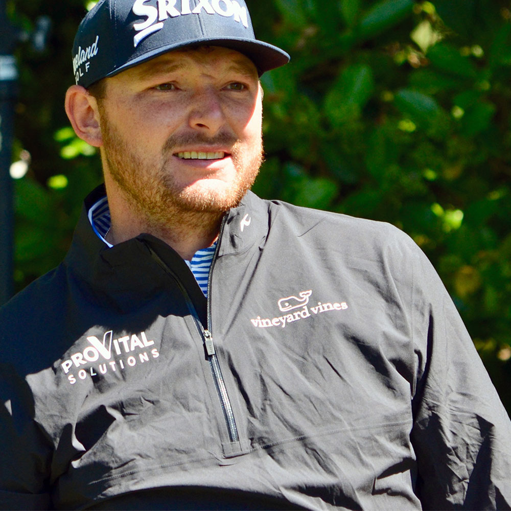 KJUS athlete Matt Nesmith wearing a black KJUS zip-up golf jacket with a 