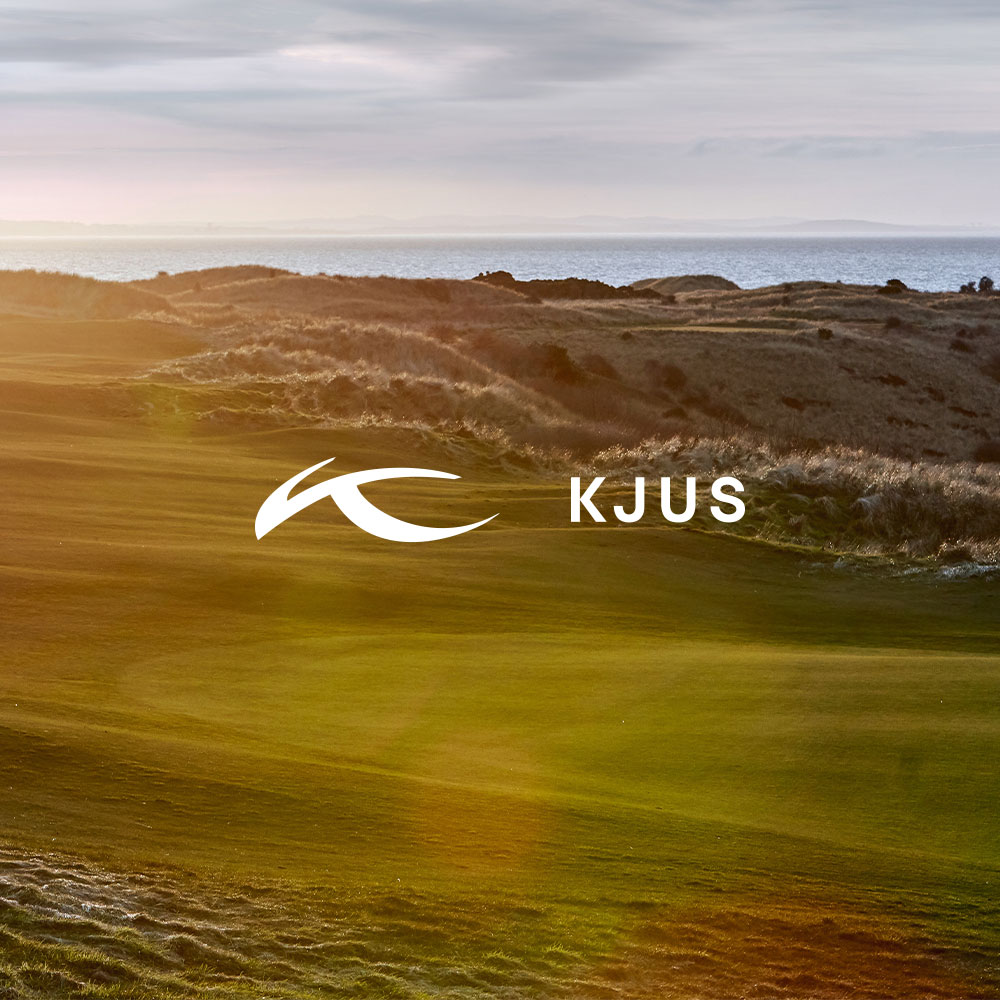 A KJUS logo overlays a sunset view of a golf course with a grassy hill landscape and calm body of water in the background.